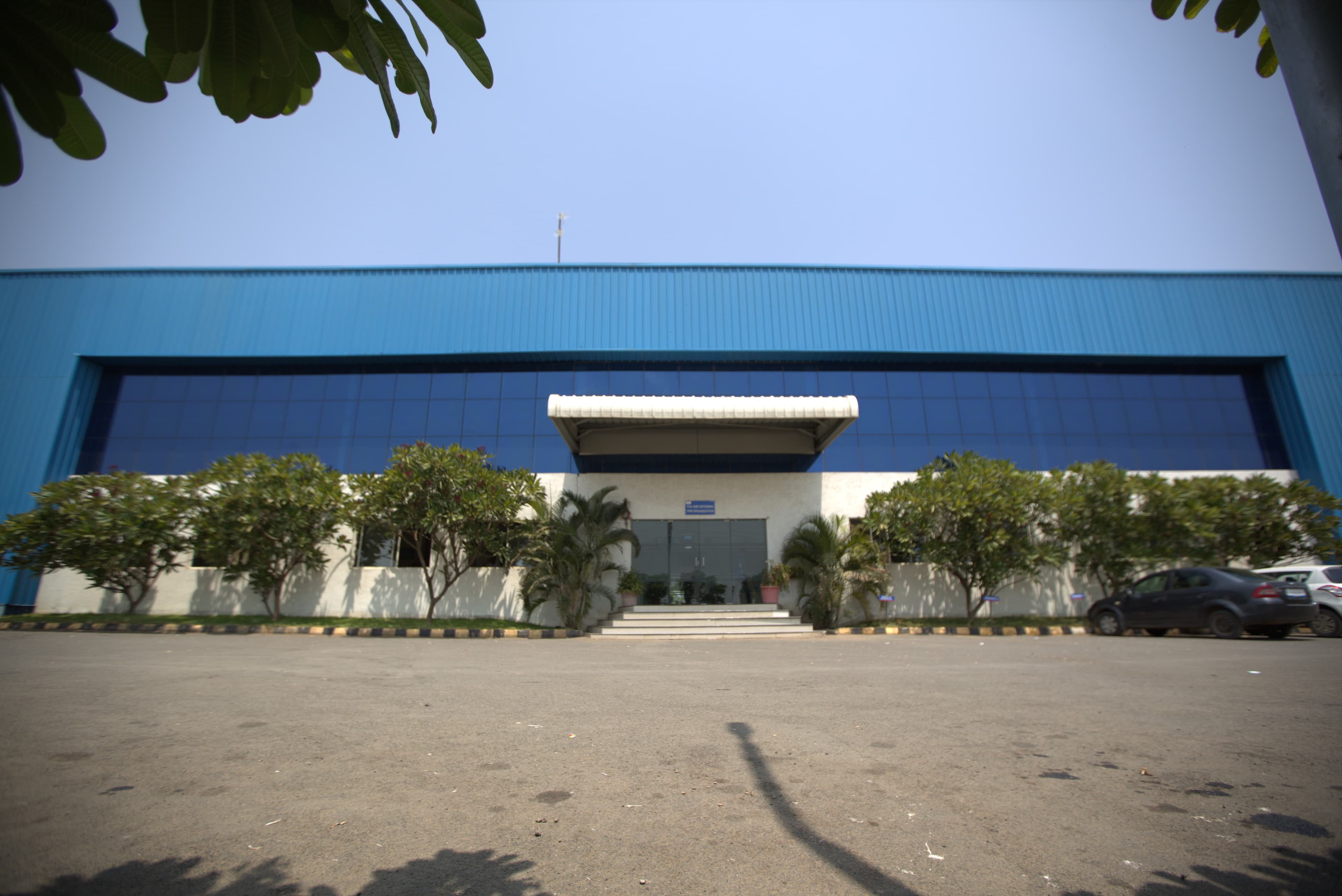 Atharva Polymers factory exterior — blue building with glass facade